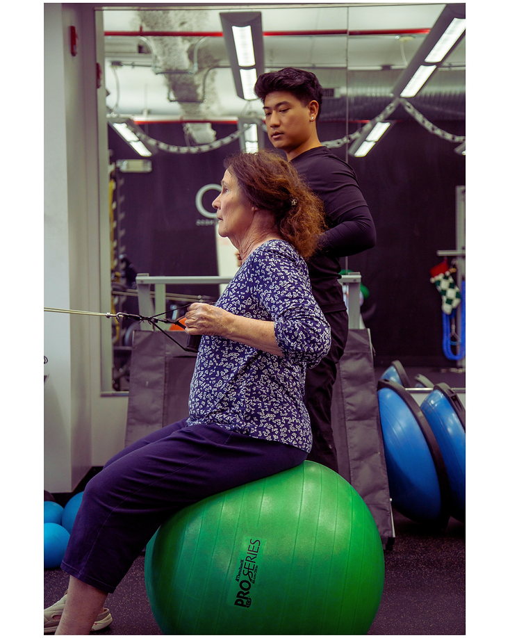 Migma Tamang observing a client's posture and form during a seated row exercise.