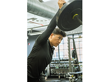 Migma Tamang, Strength and Conditioning Coach, demonstrating a single-arm overhead press with focused form.