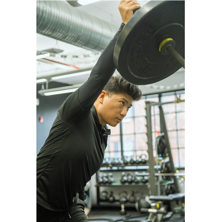 Migma Tamang, Strength and Conditioning Coach, demonstrating a single-arm overhead press with focused form.