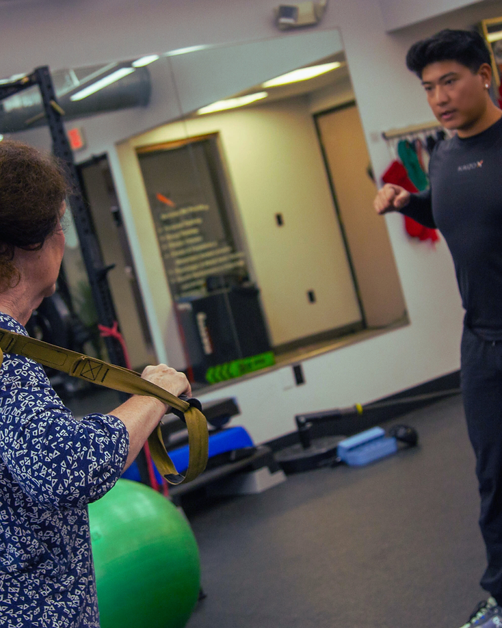 Migma Tamang guiding a client through a suspension training movement in the studio.