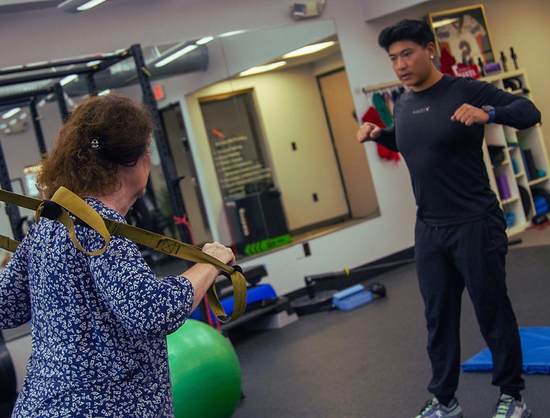 Migma Tamang guiding a client through a suspension training movement in the studio.