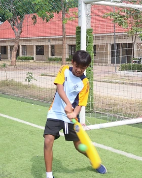 A young player mid-swing during batting practice