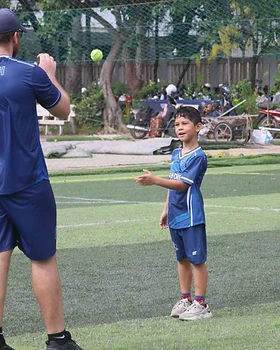 A coach running a fielding drill with a young player