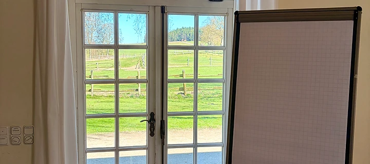 Ruhiger Coaching-Raum mit Flipchart und Blick ins Grüne