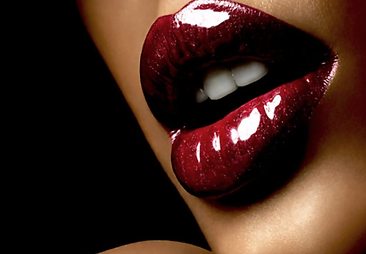 Macro study of high-gloss crimson lips against black — the house signature