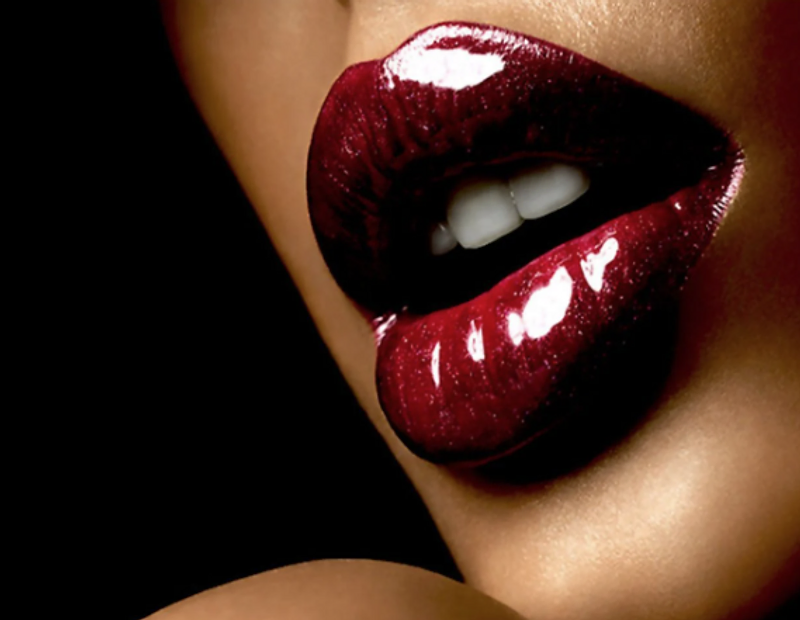 Close-up of deep crimson lips against black — the signature red of the house