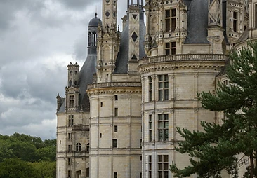 A vast historic chateau beneath heavy grey clouds