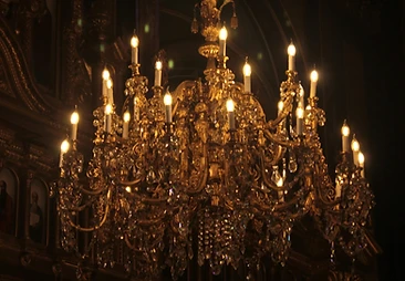 Antique gold crystal chandelier glowing in a darkened salon