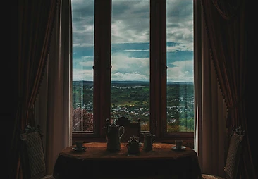 A tea service set for two in a shadowed salon framed by heavy curtains
