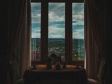 A tea service laid for two in a shadowed, curtained salon