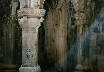 Weathered stone arches under a shaft of cool light
