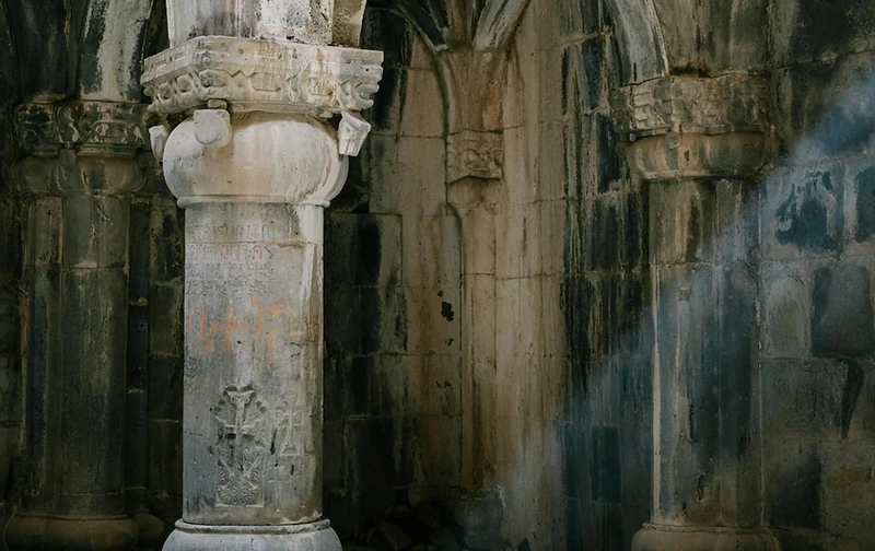 Ancient stone arches in austere cool light — cold, historical, and imposing
