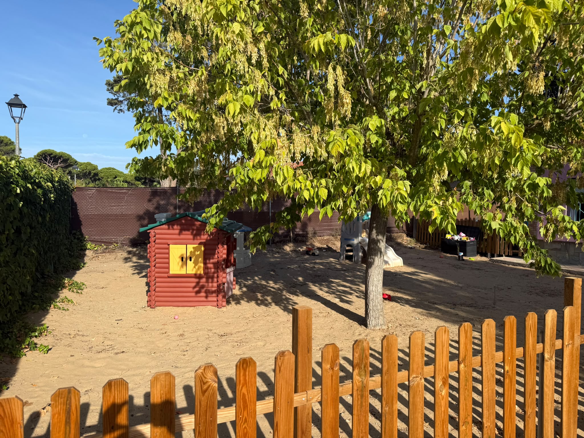 Zona de juegos exterior con casita infantil y arenero