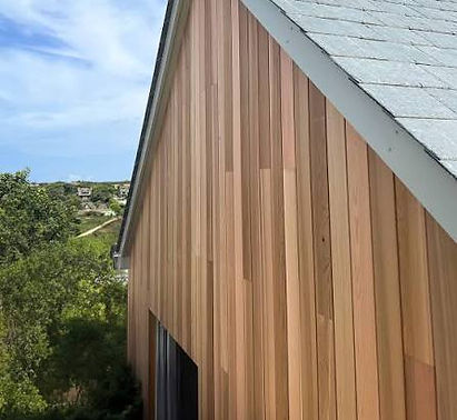House gable clad in warm-toned vertical wood siding under a clear sky