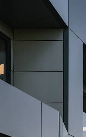 Commercial facade clad in angled grey architectural panels with glazed windows