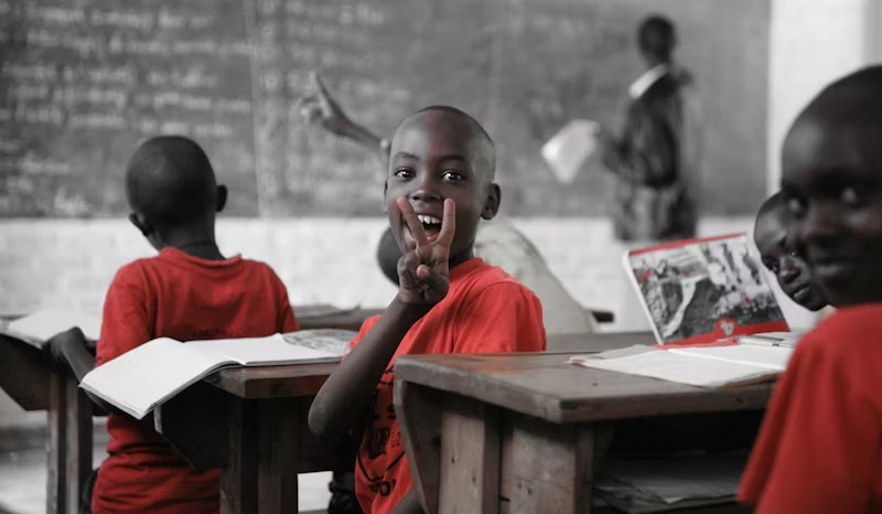 African schoolboy smiling at his desk in classroom