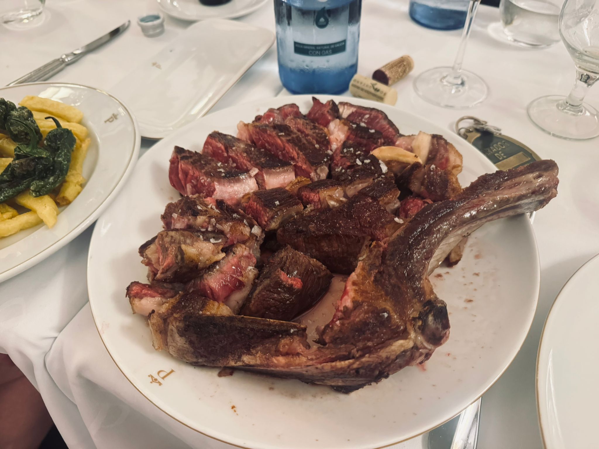 A huge txuletón Basque-style bone-in ribeye steak served on a white plate — enormous and perfectly cooked