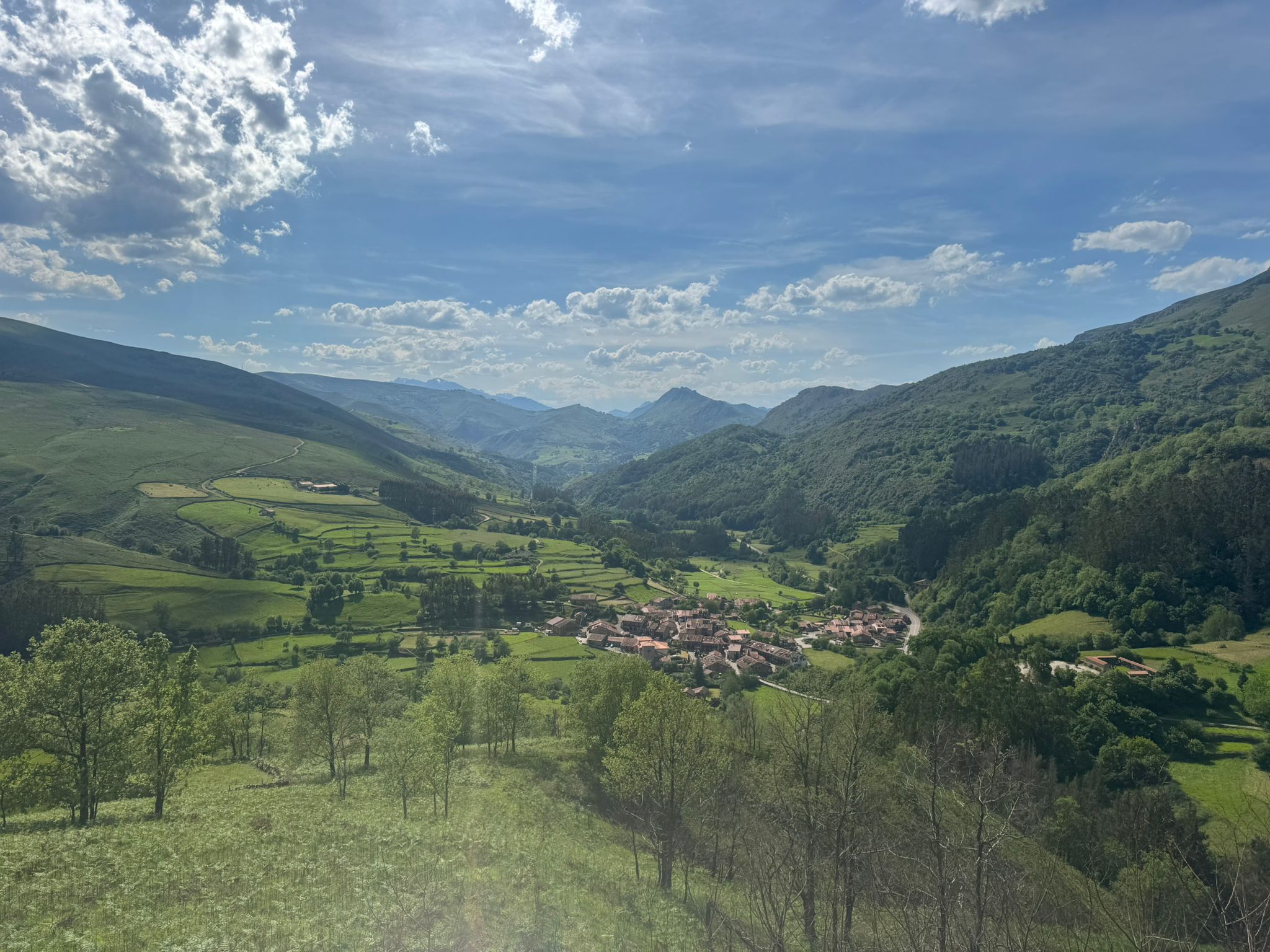 Sweeping Cantabrian valley view from above — green fields, a small village and mountains stretching into the distance