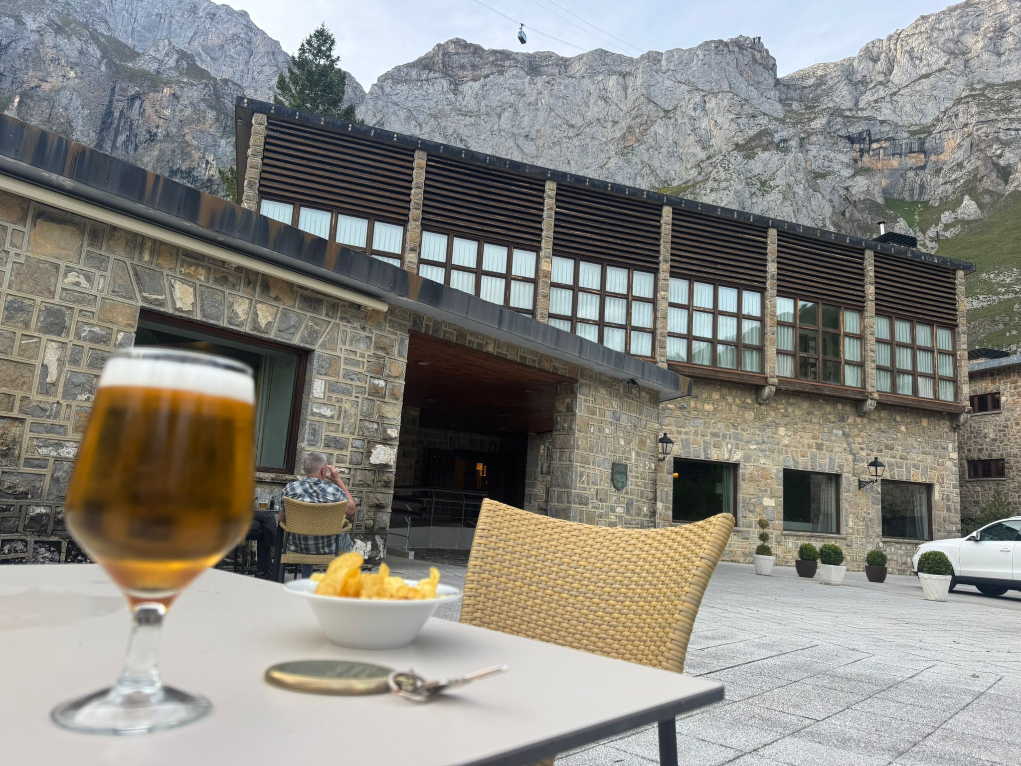 Cold beer on the terrace at Parador de Fuente Dé with the sheer Picos rock face and cable car in the background
