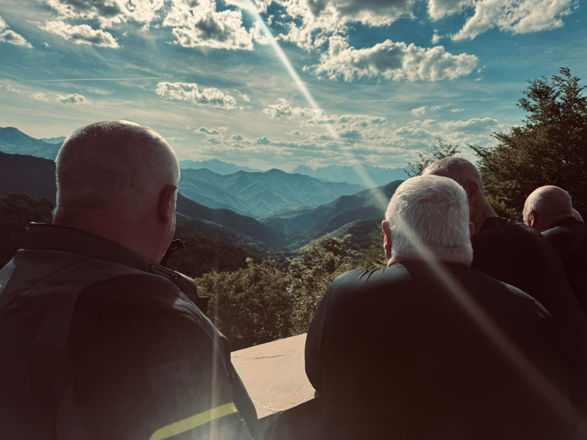 Three riders standing at a mountain viewpoint looking out over the Cantabrian mountains
