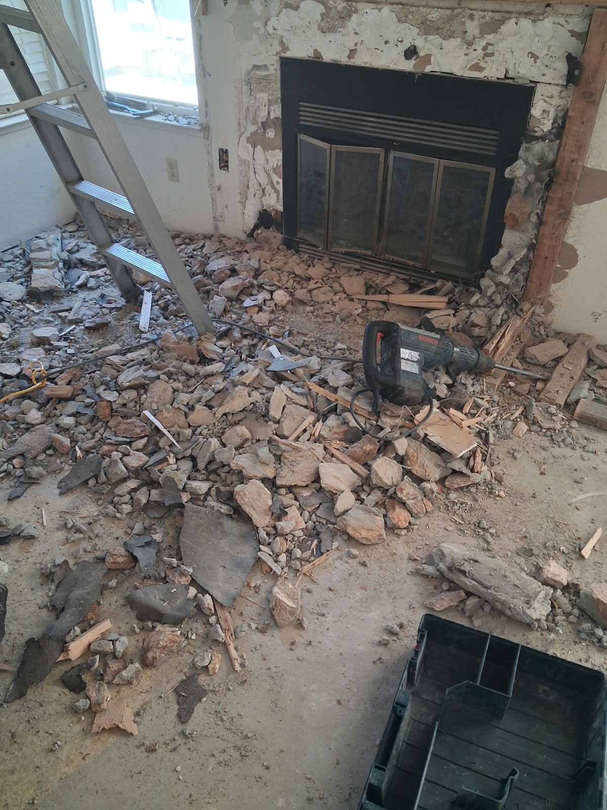 Fireplace chimney masonry surround demo — stone and brick removed, framing exposed, ready for rebuild.
