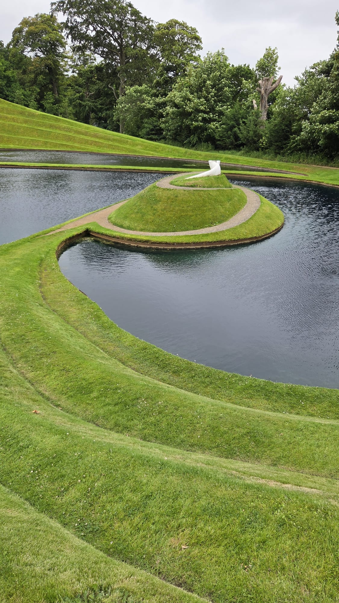 Spiralling grass terraces and causeway around a lake at Cells of Life, Jupiter Artland